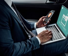 cropped view of african american businessman using laptop and smartphone in car with cyber security